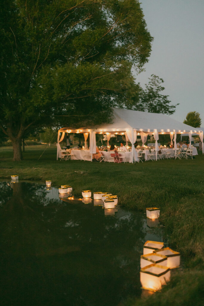Reception tent with floating lanterns in the pond in the foreground