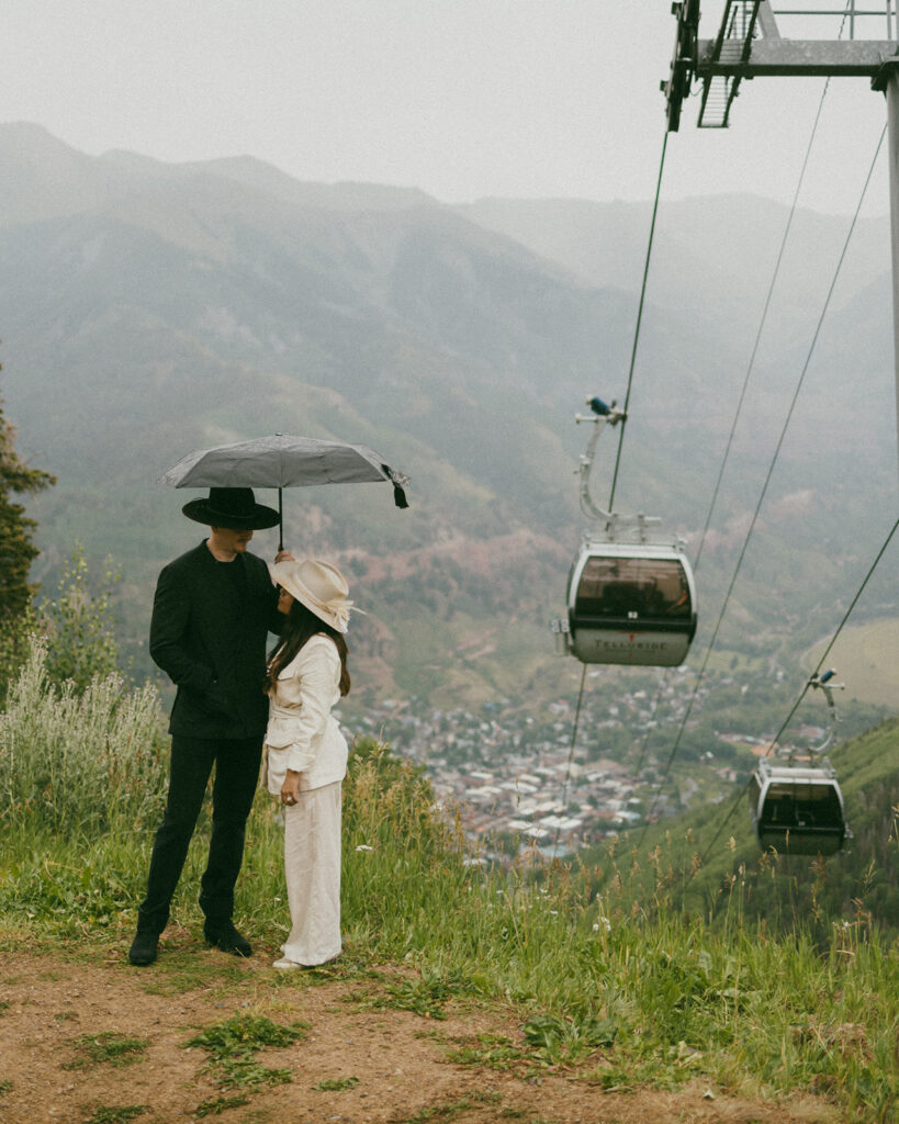 A couple on their elopement day in Telluride, CO at an overlook with the town, mountains, and gondola in the background