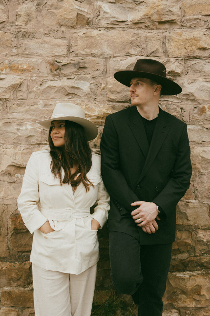 A couple on their elopement day posing in front of a brick wall