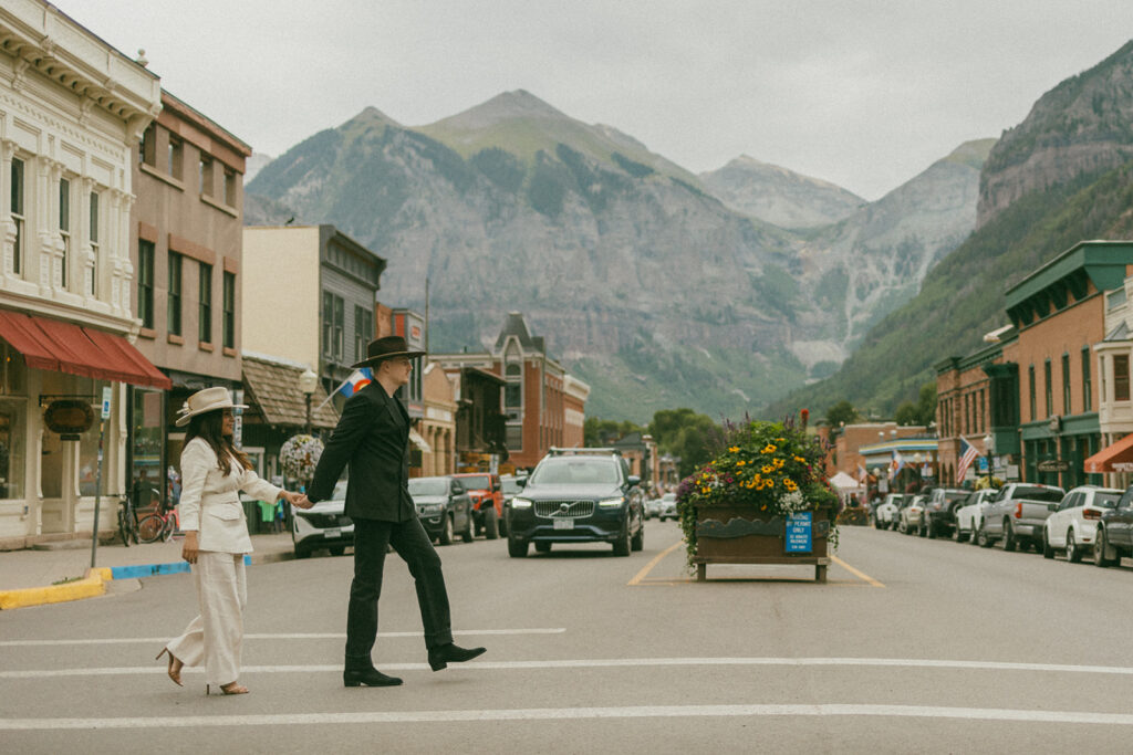 A couple on their elopement day standing in the middle of the street in Telluride, CO with a mountain view 