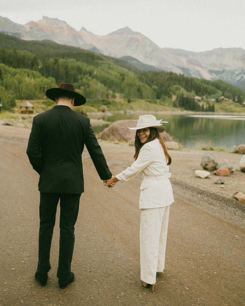 A couple on their elopement day in Telluride, CO laughing and walking around Trout Lake