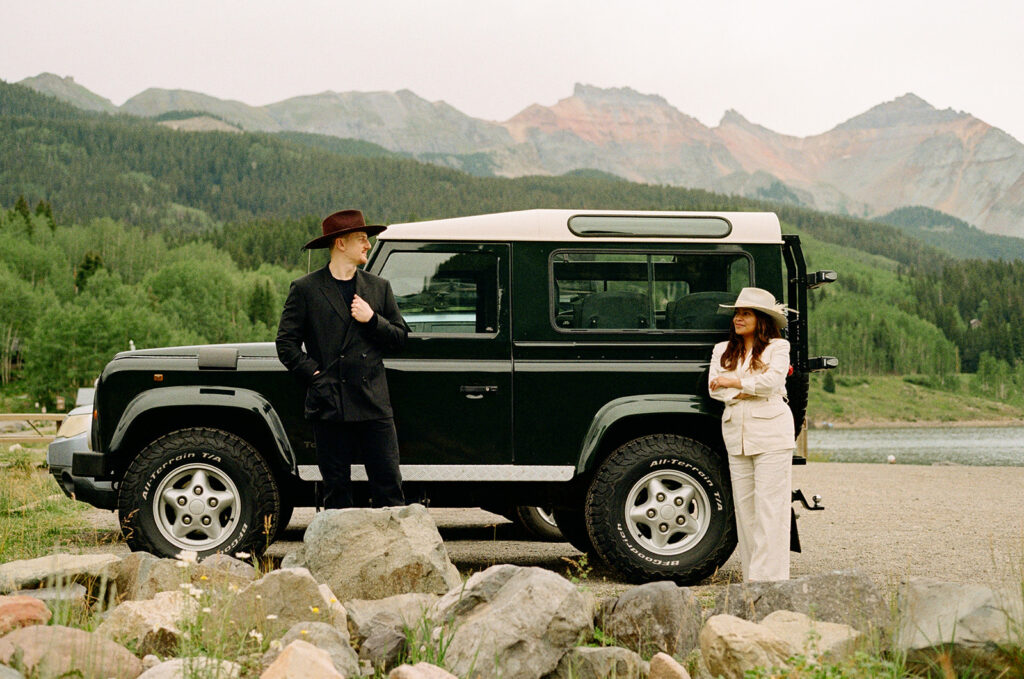 A couple on their elopement day in Telluride, CO looking at each other in front of a vintage car