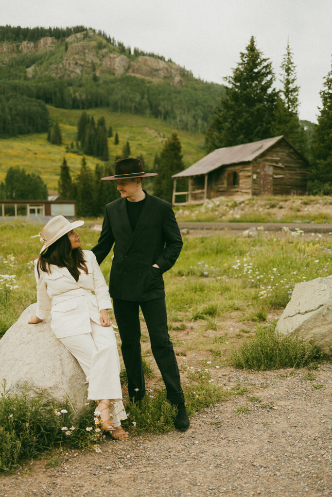 A couple on their elopement day in Telluride, CO looking at each other in front of an old wooden cabin