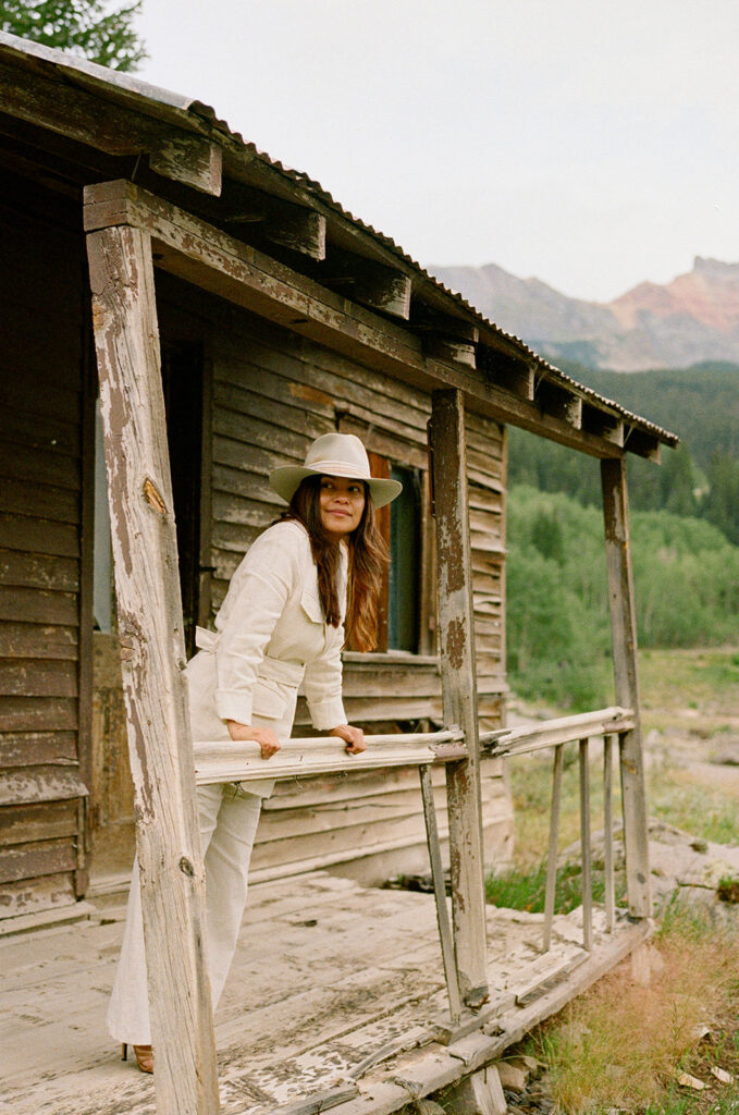 A bride on her elopement day in Telluride, CO posing in front of an old wooden cabin