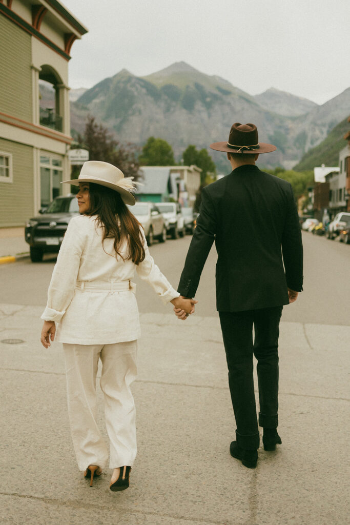 A couple on their elopement day standing in the middle of the street in Telluride, CO with a mountain view 