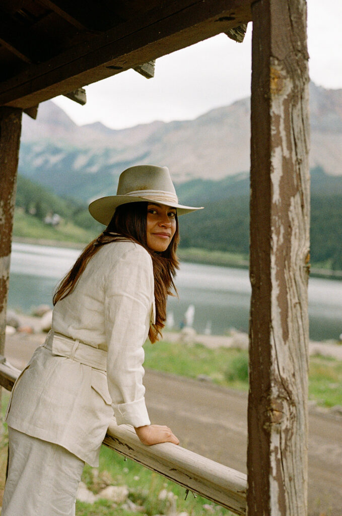 A bride on her elopement day in Telluride, CO posing in front of an old wooden cabin